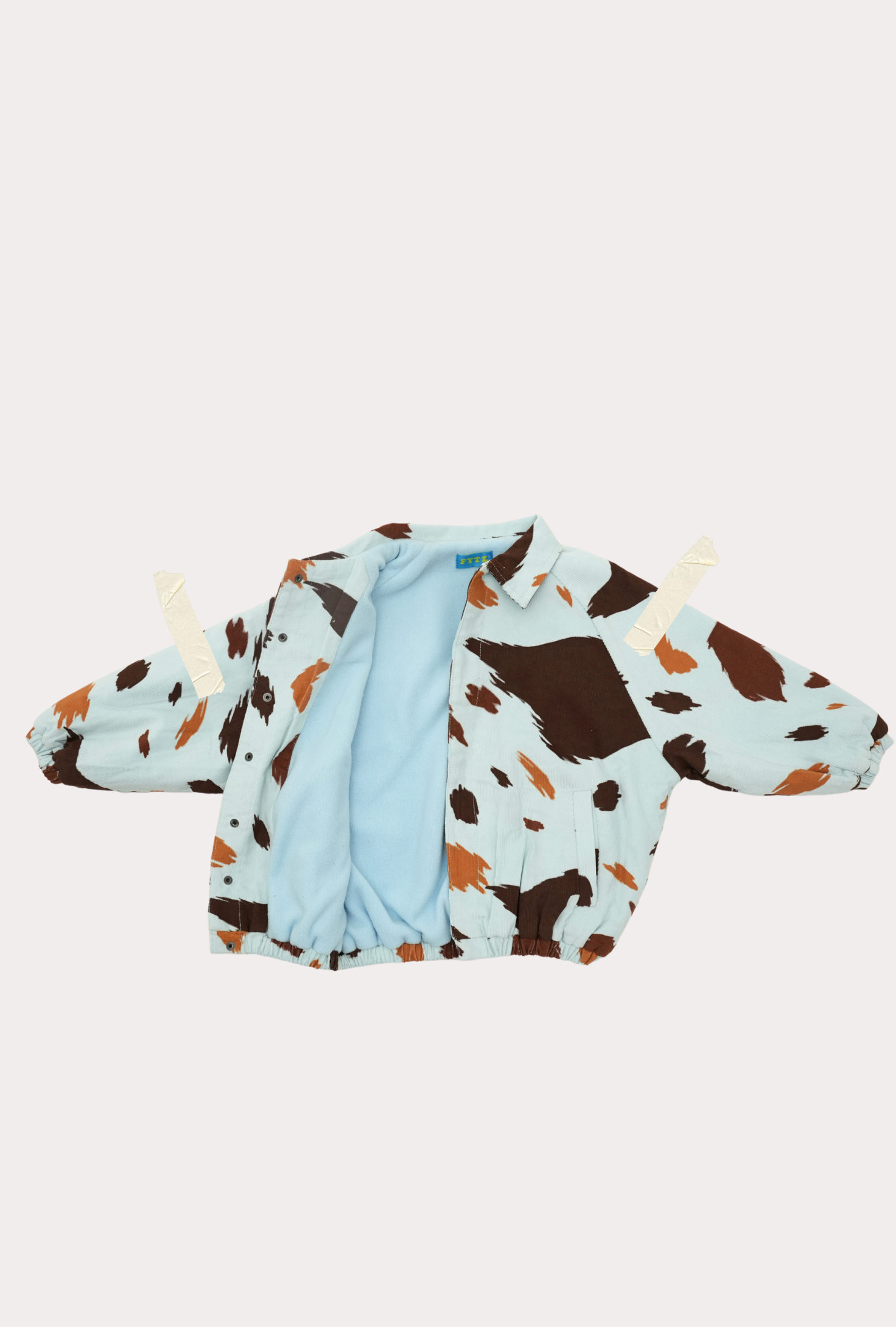 inside of Seffi kids cow print jacket with light blue fleece lining and snap buttons