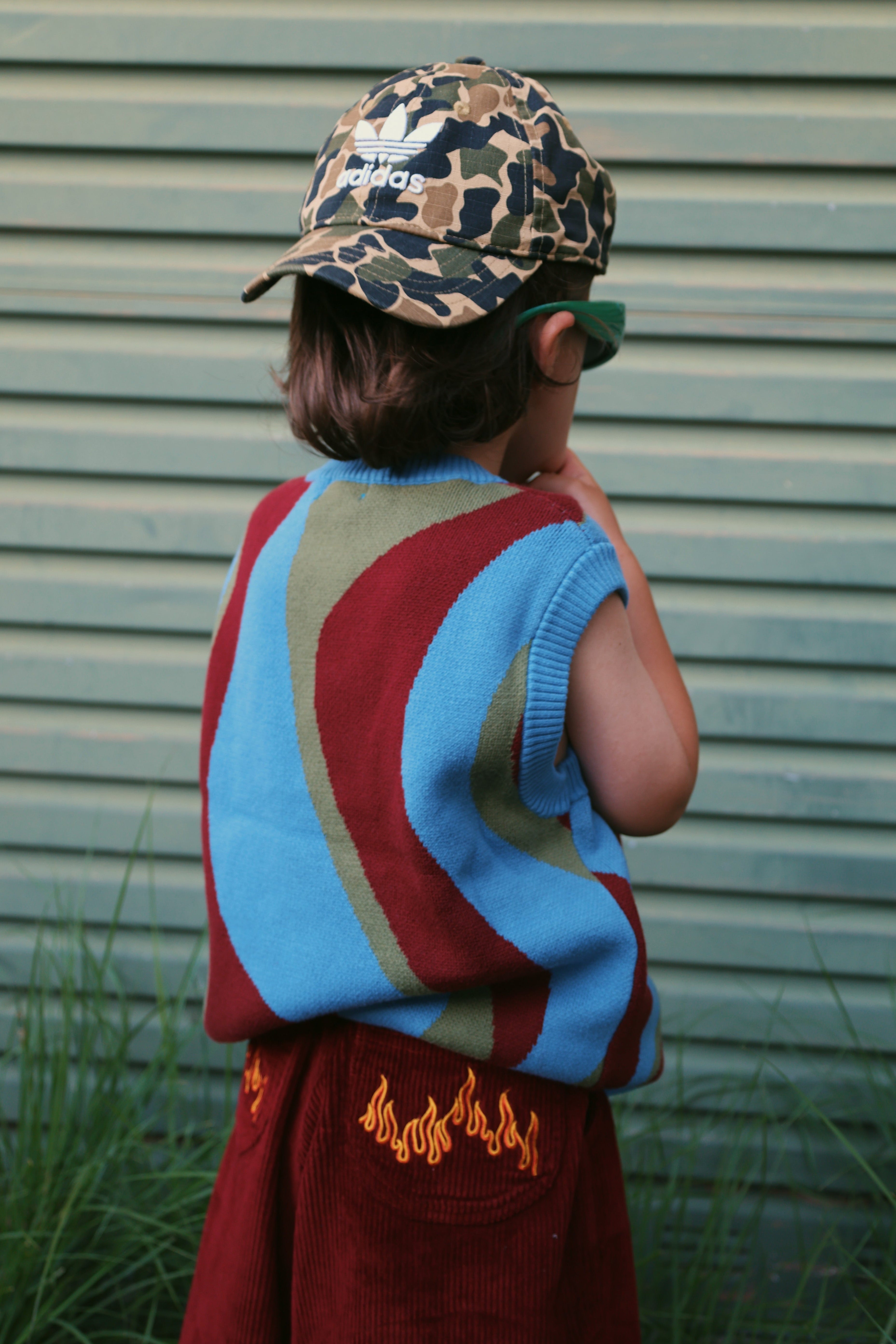 Child wearing colourful johnny vest in cherry ice swirl and blaze cord pants in flame