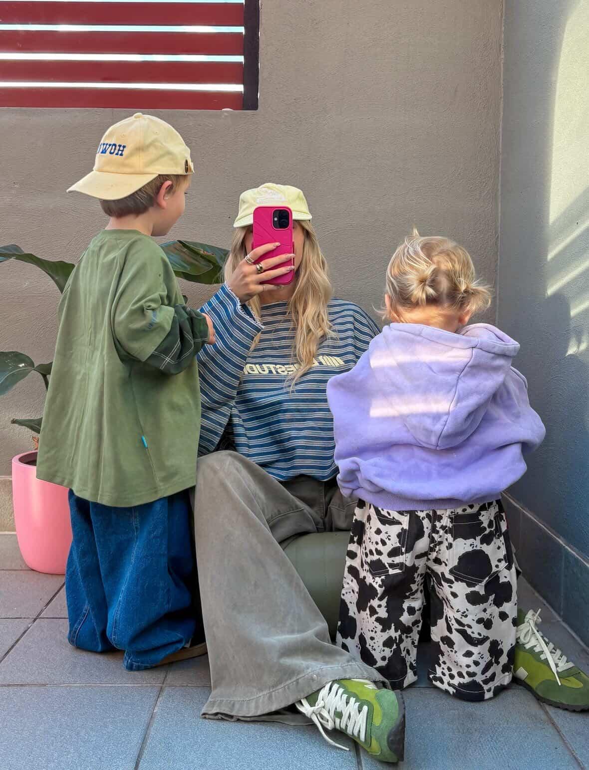 Ash Sambell taking a selfie with two children outdoors on a sunny day. ollie